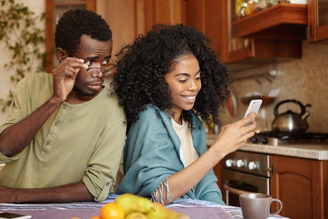 jealous-curious-black-man-holding-glasses-spying-his-girlfriend-s-mobile-phone-while-she-is-typing-message-her-lover-smiling-happily-betrayal-unfaithfulness-infidelity-lack-trust